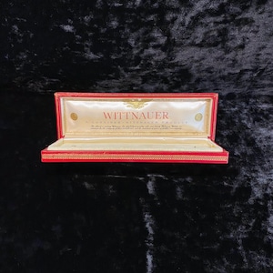 May include: Red velvet lined box with a gold trim and the words "Wittnauer A Longines Wittnauer Product" on the lid.