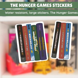 May include: Stickers featuring the book covers from The Hunger Games series. The stickers include titles like "The Hunger Games," "Catching Fire," and "Mockingjay." The text "Water resistant, large stickers. The Hunger Games" is also visible.