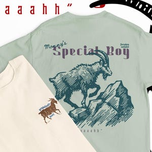 May include: Two t-shirts with graphic designs. One is cream-colored with a small goat illustration, the other is light green with a goat on a mountain illustration. Text on the shirts reads "Mommy's Special Boy" and "aaaaahhh".