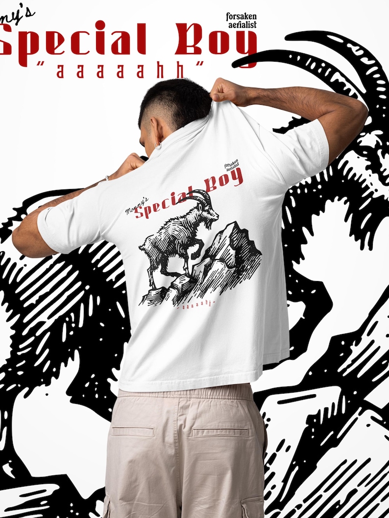 May include: White t-shirt with the text "Special Boy" in red and a graphic of a mountain goat. The shirt also features the text "aaaaahhh" and "forsaken aerialist". The shirt is being held up by a person.