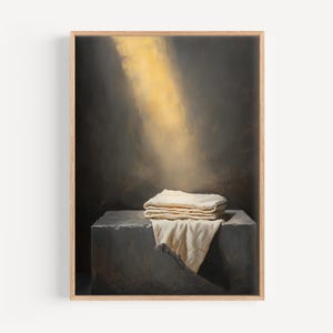 Puede incluir: Una pintura de un paño blanco doblado sobre una superficie de piedra gris con un rayo de luz que brilla desde arriba.