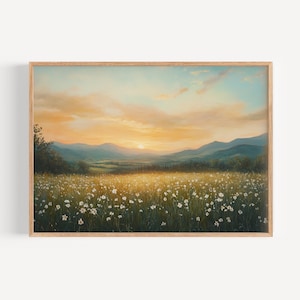 May include: A framed landscape art print depicts a field of white wildflowers bathed in golden sunlight. Mountains are in the background under a sky of orange and blue hues. The artwork is in a wooden frame.