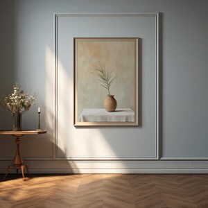 May include: A still life painting of a single branch with leaves in a brown ceramic vase on a white tablecloth. The painting is framed and hanging on a light blue wall.