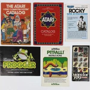 May include: A collection of six vintage Atari and Activision video game manuals and catalogs. The items feature colorful illustrations, including a frog, a boxer, and various game scenes, with printed text titles like The Atari Catalog, Frogger, and Pitfall.