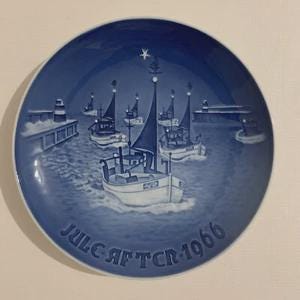May include: A blue and white decorative plate featuring a nautical scene with several sailboats on the water. The plate has a dark blue border and the text "JULEAFTEN 1966" is printed at the bottom.