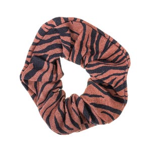 Könnte beinhalten: Ein Haargummi mit einem braunen und schwarzen Zebrastreifenmuster. Das Haaraccessoire ist aus Stoff gefertigt und hat eine kreisförmige Form. Das Haargummi ist ein Haaraccessoire.