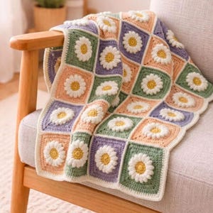 May include: A handmade crochet blanket composed of square motifs, each featuring a white daisy with a yellow centre. The squares are arranged in a grid pattern using alternating soft pastel colours including sage green, lavender, and peach yarn.