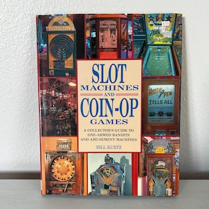 May include: A book titled "Slot Machines and Coin-Op Games" with a collage of vintage arcade game images. The cover features a central title block with blue text and the author's name. The book is a collector's guide to one-armed bandits and amusement machines.