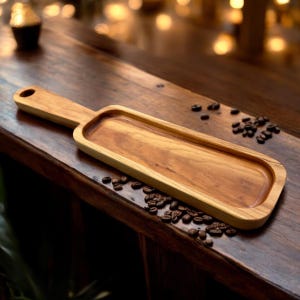 May include: A long, rectangular wooden serving tray with a handle. The tray is made of light brown wood and has a smooth, polished finish. The tray is perfect for serving snacks, appetizers, or desserts.