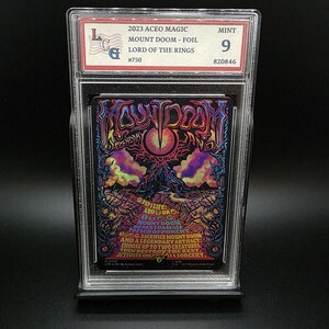 May include: A graded trading card with the text "MOUNT DOOM - FOIL" from the Lord of the Rings. The card has a vibrant, psychedelic design with an eye and mountain imagery. The card is encased in a clear plastic holder.