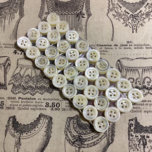 36 boutons anciens en nacre de France de 9 mm, quatre trous, carte originale. Plusieurs cartes disponibles. Confection de robes, costumes, cyclisme.