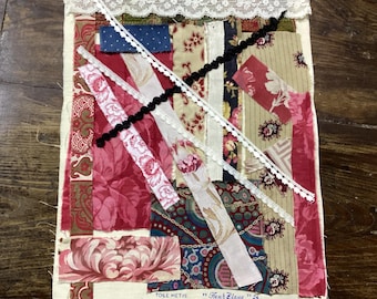 Könnte beinhalten: Ein Patchwork-Textil mit cremefarbenem Hintergrund, das verschiedene Stoffreste in Rot-, Rosa- und Cremetönen aufweist. Das Design umfasst florale Muster, Streifen und Spitzenbesatz. Der Text "TOILE METIS" und "Fleur Bleue" sind sichtbar.