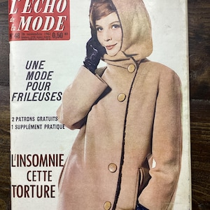 Könnte beinhalten: Vintage Zeitschriften-Cover mit einer Frau in einem beigefarbenen Mantel mit Kapuze und schwarzen Handschuhen. Die Zeitschrift trägt den Titel "L'ECHO de la MODE" mit französischem Text. Retro-Ästhetik.