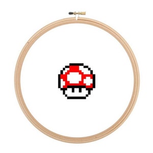 May include: A wooden embroidery hoop with a red and white pixelated mushroom design.