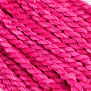 May include: Close-up of a bundle of pink embroidery floss. The floss is tightly wound and has a slight sheen.
