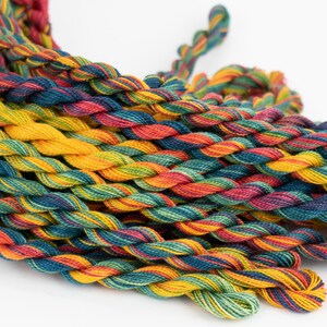 May include: A collection of multi-colored embroidery floss spools in shades of red, orange, yellow, green, blue, and purple. The floss is twisted and piled together in a random pattern.