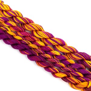 May include: Three strands of embroidery floss in shades of orange, yellow, and purple. The floss is twisted together and has a variegated pattern.