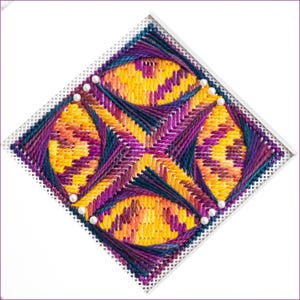 May include: A colorful cross-stitch design with a geometric pattern of overlapping circles in shades of yellow, orange, purple, and blue. The design is stitched on white Aida cloth and accented with white beads.