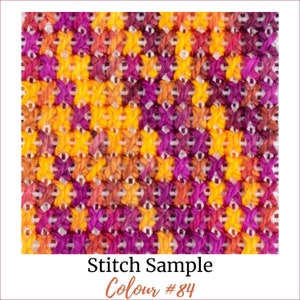 May include: A close-up of a cross-stitch fabric sample with a diagonal pattern in shades of orange, yellow, and purple. The text "Stitch Sample Colour #84" is printed below the fabric.