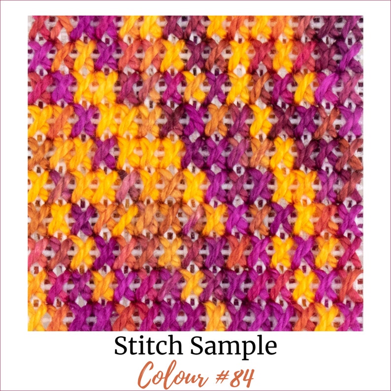 May include: A close-up of a cross-stitch fabric sample with a diagonal pattern in shades of orange, yellow, and purple. The text "Stitch Sample Colour #84" is printed below the fabric.
