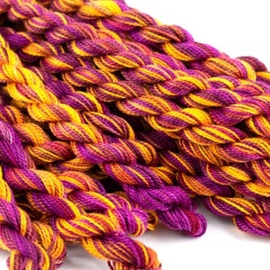 May include: A close-up of a bundle of embroidery floss in shades of purple, orange, and yellow.