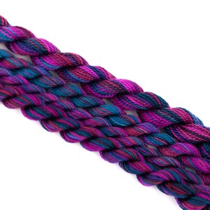 K&ouml;nnte beinhalten: Drei Kn&auml;uel Stickgarn in den Farben Lila, T&uuml;rkis und Schwarz. Das Garn ist gedreht und hat ein mehrfarbiges Muster.