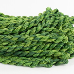 May include: A pile of green and yellow embroidery floss, twisted together in a rope-like shape.