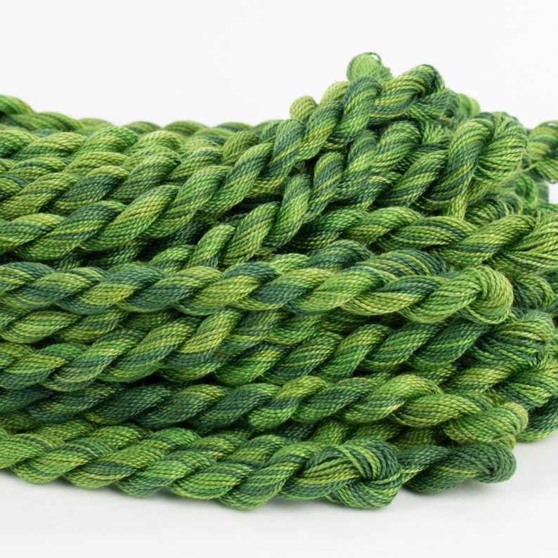 May include: A pile of green and yellow embroidery floss, twisted together in a rope-like shape.