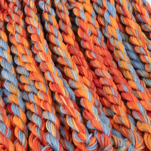 May include: Close-up of a bundle of embroidery floss in shades of orange and blue.