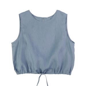 May include: A sleeveless, light blue top with a round neckline and a drawstring waist. The top is made of a soft, textured fabric and features a small zipper at the back of the neck. The bottom hem is gathered, and the drawstring is tied in a bow.
