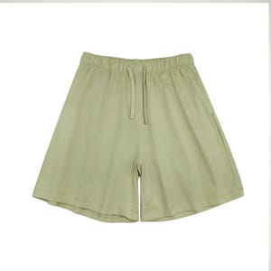 May include: Pale green shorts with an elasticated waistband and a drawstring. These shorts have a loose fit and are made from a soft, lightweight material. The shorts are a solid colour and have a simple, minimalist design.