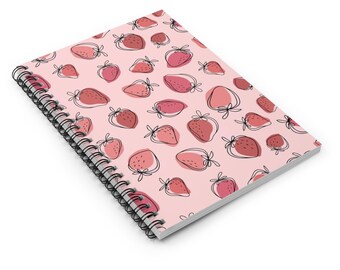 May include: A pink spiral notebook with a pattern of red and pink strawberries. The strawberries are drawn in a simple, hand-drawn style.