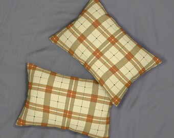 May include: Two rectangular throw pillows with a cream-colored background and a plaid pattern in shades of orange, brown, and green. The pillows are arranged on a gray surface.