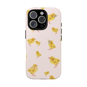 May include: A phone case with a pale pink background featuring a repeating pattern of yellow watercolor chicks. Some chicks have small bows or flowers. The case has a black camera module and black side buttons.