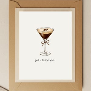 K&ouml;nnte beinhalten: Eine wei&szlig;e Karte mit einer handgezeichneten Illustration eines Kaffeemartinis mit Kaffeebohnen darauf. Der Text "just a tini bit older" steht unter dem Martini.