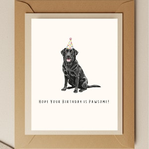 May include: A black Labrador Retriever wearing a colorful party hat. The text "HOPE YOUR BIRTHDAY IS PAWSOME!" is below the dog.