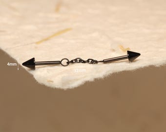 May include: A black industrial barbell with cone-shaped ends, connected by a small chain. The barbell is 3.2 cm long, with the cone ends measuring 4 mm. The jewellery is displayed on a textured, off-white surface.
