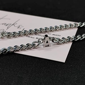 May include: A silver chain necklace with a silver letter 'A' charm. The necklace is on a white card with the text 'Thanks, I support so much small business'.