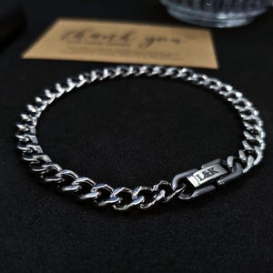 May include: A silver chain bracelet with a clasp that reads "L&K".