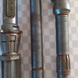 Op de afbeelding: Drie metalen staven met een zilveren en roestige afwerking. De staven hebben een getextureerd oppervlak en zijn van verschillende lengtes.
