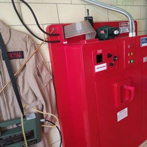 May include: A red metal box with a door and a handle. The box has a variety of wires and cables attached to it. There is a sign on the box that reads "DANGER - DO NOT TOUCH WIRES - BRANCH CIRCUITS ONLY".