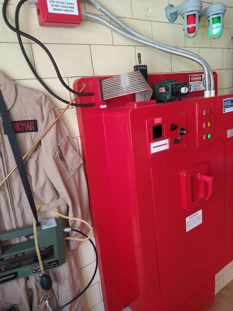May include: A red metal box with a door and a handle. The box has a variety of wires and cables attached to it. There is a sign on the box that reads "DANGER - DO NOT TOUCH WIRES - BRANCH CIRCUITS ONLY".