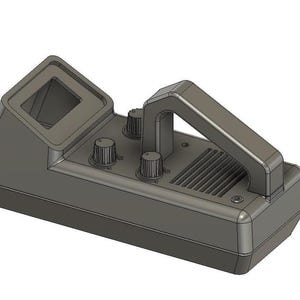 May include: A grey metal detector featuring a handle, three control knobs, and a small rectangular aperture. The device has a ridged speaker section and a square opening on top.