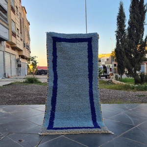 Könnte beinhalten: Ein hellblauer Teppich mit einer dicken, flauschigen Textur. Der Teppich hat einen blauen und gelben Rand.