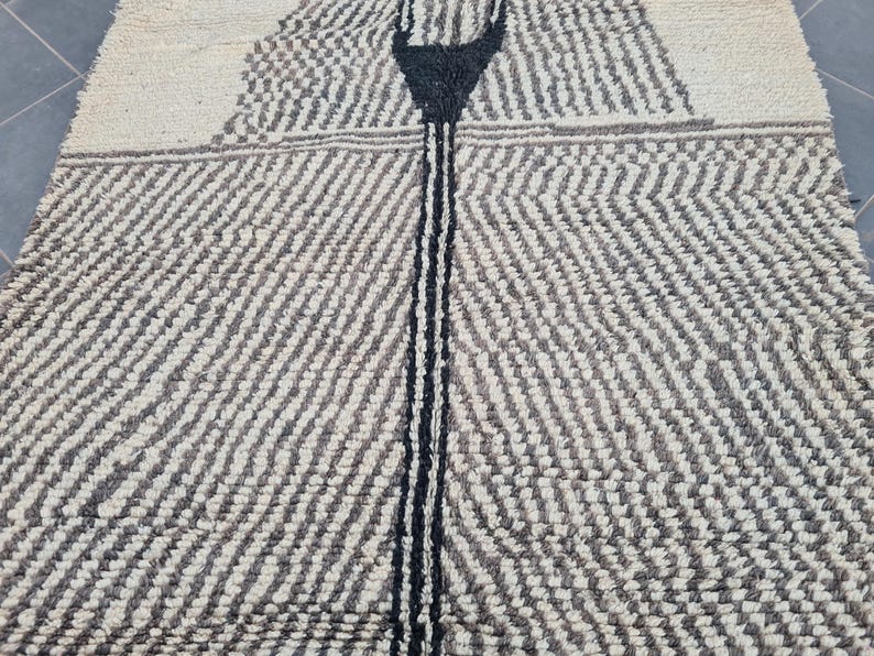 May include: A white and black patterned rug with a black stripe down the center. The rug has a textured, woven look.
