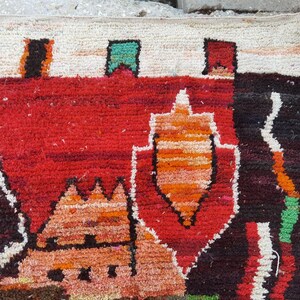 May include: A colorful rug with a geometric design featuring a variety of shapes and colors, including red, orange, black, white, and green.