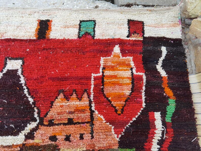 May include: A colorful rug with a geometric design featuring a variety of shapes and colors, including red, orange, black, white, and green.