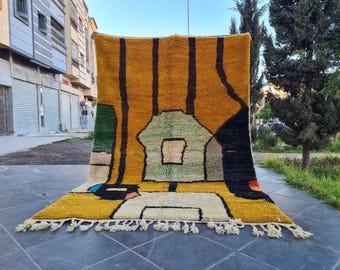 May include: A colorful, abstract rug with geometric shapes in shades of yellow, green, black, and white. The rug has a fringe border and is made of wool.