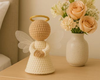 May include: A handcrafted crochet angel figurine with a golden halo and delicate wings. The angel is dressed in a cream-colored dress and has a tan head and hands. A small vase of peach-colored roses and other flowers sits nearby.