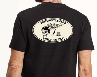 May include: Black t-shirt with a white oval graphic that says "Motorcycle Club" and features a skull wearing a helmet with wings. The graphic also says "Fear Nothing" and "Built to Fly."